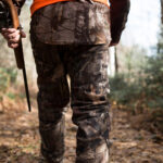 Hunter with rifle walking in forest